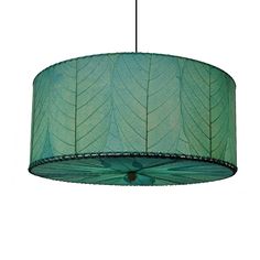 a green lamp hanging from a ceiling with leaves printed on the lampshade above it