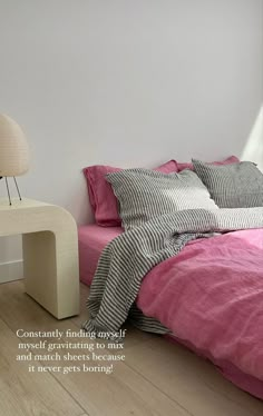 there is a bed with pink sheets and pillows