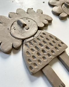 three clay sculptures made to look like flowers with holes in the middle one is holding a spatula