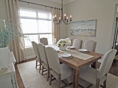 a dinning room table with white chairs and a chandelier hanging from the ceiling