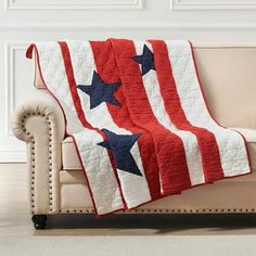 an american flag quilt sitting on top of a couch next to a white sofa and chair