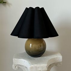 a table with a lamp on top of it next to a vase and potted plant