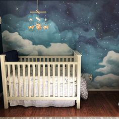 a baby's room with a crib and stars painted on the wall behind it