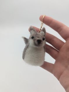 a hand holding a tiny stuffed animal keychain