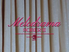 the words melodrama soberi written in pink on a white curtained background