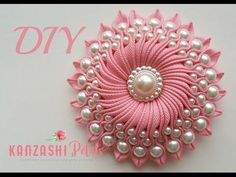 a pink and white brooch with pearls on it