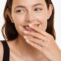 a woman is smiling and holding her hand to her mouth with the ring on her finger