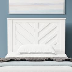 a bed with a white headboard against a blue wall