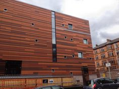 two cars parked in front of a building with wooden panels on it's side