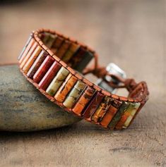 two leather bracelets with multicolored beads on top of a rock next to a stone