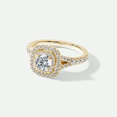 a yellow gold engagement ring with diamonds on the band and a round center stone in the middle