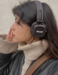 a woman wearing headphones with her hand to her ear and looking off into the distance