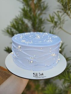 a blue cake with white frosting and sprinkles is being held up