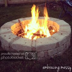 a fire pit sitting on top of a lush green field