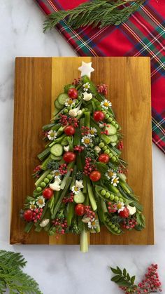 a christmas tree made out of vegetables on a cutting board next to other holiday decorations