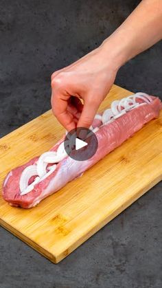 a person is cutting meat on a wooden board