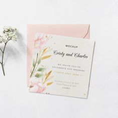 a pink and white wedding card with flowers on it, next to a flower bouquet