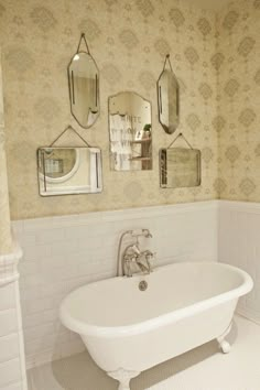 a white bath tub sitting under three mirrors