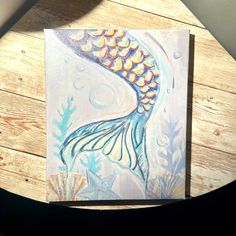 an acrylic painting of a mermaid fish on wood planks with sunlight coming through the window