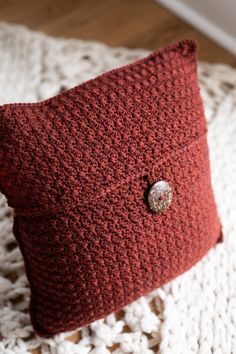 a crocheted pillow with a button on it