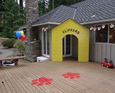 a child's play area in front of a house decorated with balloons and paw prints