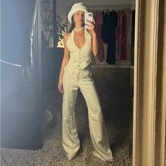 a woman taking a selfie in front of a mirror wearing a white jumpsuit