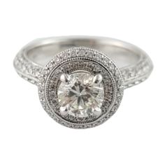 a white gold ring with diamonds on the sides and a halo setting in the middle