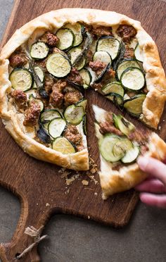 a pizza on a wooden cutting board with slices taken out of it and one slice missing