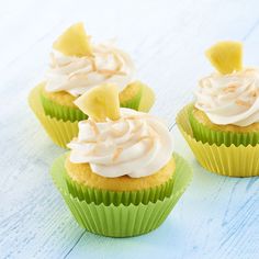 four cupcakes with white frosting and pineapple on top