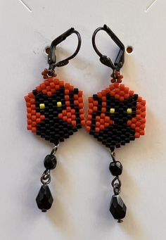 the beaded earrings are designed to look like an orange and black cat with yellow eyes