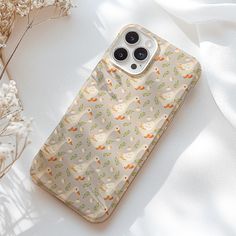 an iphone case sitting on top of a white surface next to dried plants and flowers