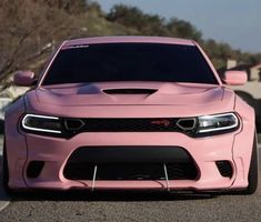 the pink dodge charger is parked on the street