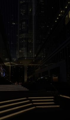 stairs lit up at night in front of tall buildings with lights on the sides and windows