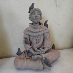 a statue of a man sitting on top of a white surface with birds perched on him