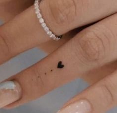 two people with wedding rings on their fingers, one has a small heart tattoo on the middle finger