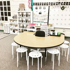 a table and chairs in a room with many shelves on the wall behind it,