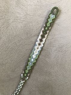 a green and white bracelet on top of a gray cloth covered table with an umbrella