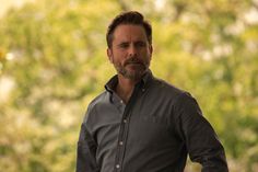 a man with a beard standing in front of trees