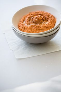 two white bowls filled with red sauce on top of a paper towel next to each other