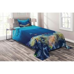 an ocean themed bed set with blue sheets and pillow cases on the bottom, in front of a window