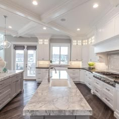 a large kitchen with marble counter tops and white cabinets, along with an island in the middle