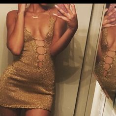 a woman taking a selfie in front of a mirror wearing a gold mini dress