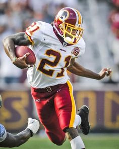 a football player running with the ball in his hand and another person behind him on the field