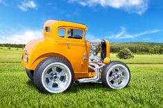 an orange truck parked on top of a lush green grass covered field in front of a blue sky