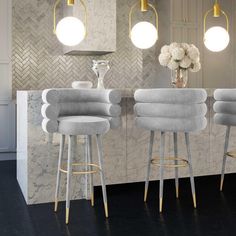 three modern bar stools in front of a marble countertop with flowers on it