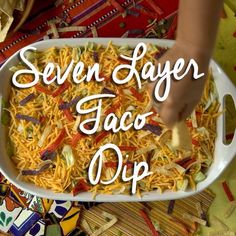 a person scooping up some taco dip into a casserole dish with the words seven layer taco dip