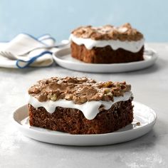 two pieces of cake sitting on top of white plates with frosting and toppings