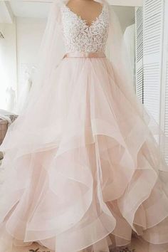 a wedding dress on display in front of a white wall with a pink ribbon around the waist