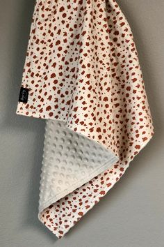 a white and brown polka dot blanket hanging on a wall next to a gray wall