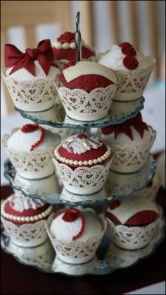 three tiered trays with cupcakes and muffins on them are adorned with red bows